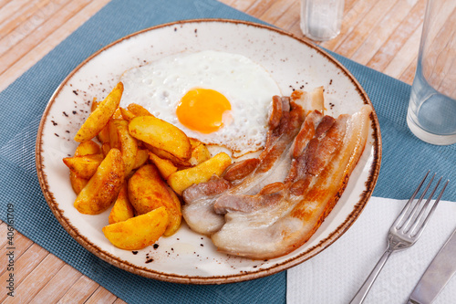 Plate of fried meat and potatoes served with fried egg