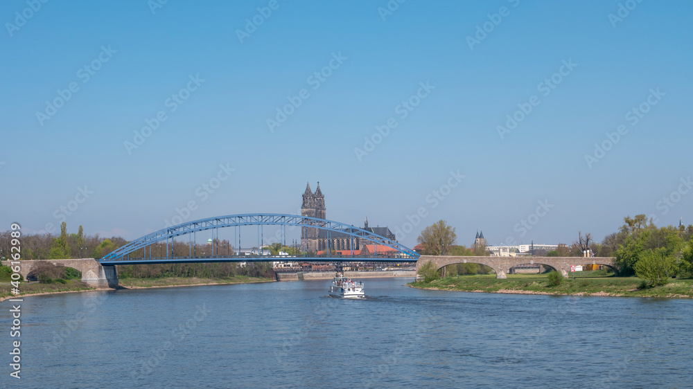 Panoramic view over downtown of Magdeburg, old town, Elbe river, bridges and Magnificent Cathedral at early Spring, Germany, at sunny day and clear blue sky with a tour boat.