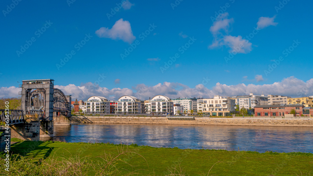 Panoramic view over modern living houses, and old railway bridge at Elbe river bank near city park and historical downtown at Spring in Magdeburg, Germany.