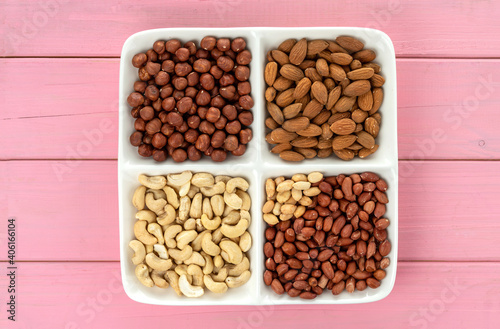 Four kinds of nuts in four compartments of combination plate: cashews, peanuts, hazelnuts, and almonds.