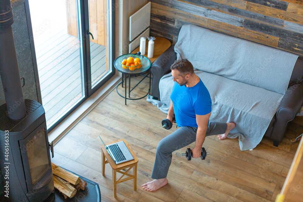 A man trains at home online using a tutorial from the Internet. Exercise for legs. A man trains at home online using a tutorial from the Internet. Exercise for legs.