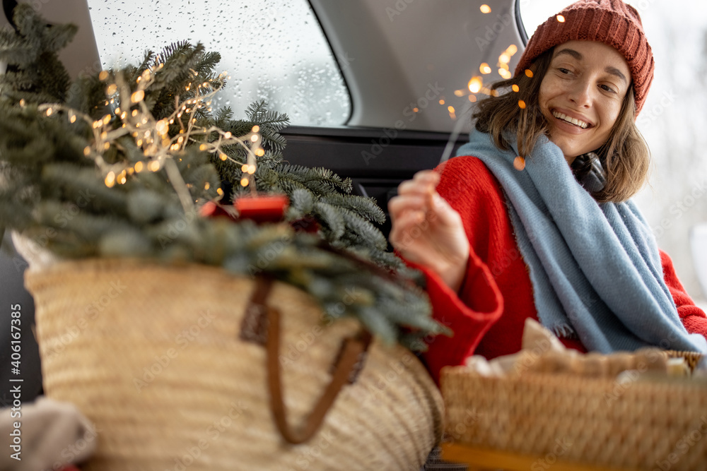 Woman smiling and looking at sparkler while sitting in car trunk 