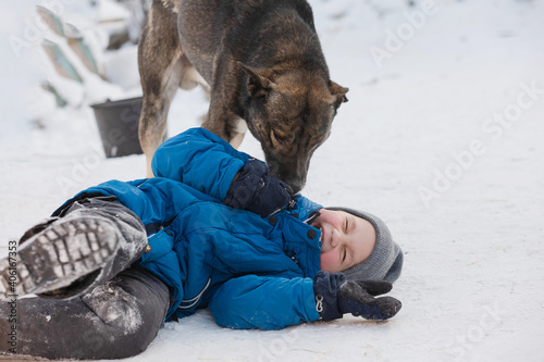 A boy plays outside with a dog from a shelter in winter. Concept of patronage assistance in animal shelters.