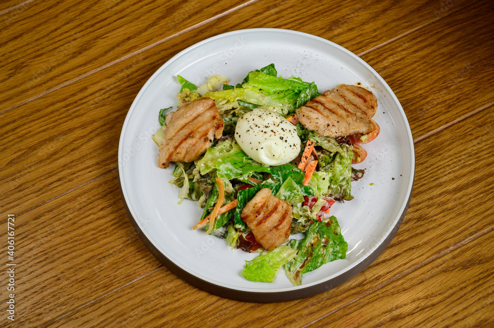 Caesar salad with croutons, quail eggs, cherry tomatoes and grilled chicken in wooden table Caesar salad with croutons, quail eggs, cherry tomatoes and grilled chicken in wooden table