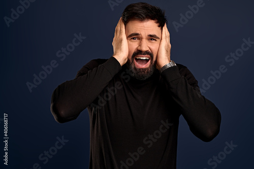 Shocked concerned young man stare speechless and distressed at camera, grab head with both hands and gasping, look worried and concerned as facing difficulties, standing troubled Blue background