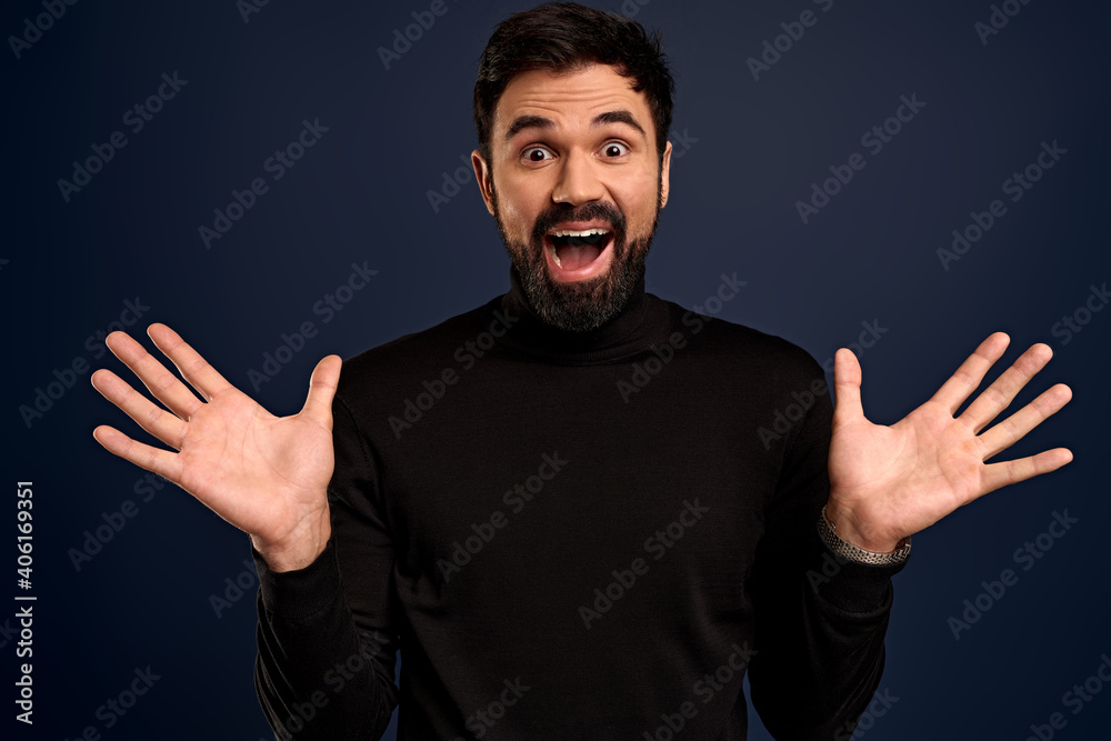 Excited, happy smiling bearded 25s man raise hands and grin joyfully, receive excellent news, gasping wondered and amused, triumphing, got promoted, standing Pacific Blue background cheerful