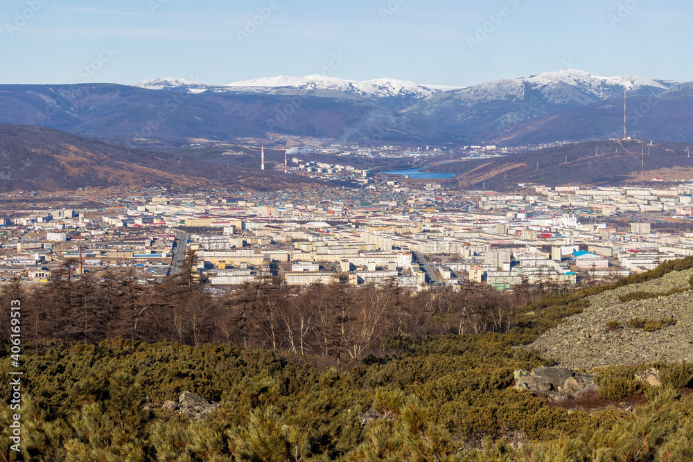 View from the mountain to the city of Magadan. A large city in a valley among the mountains. Beautiful autumn cityscape. Street and building view. Magadan, Magadan region, Siberia, Russian Far East.
