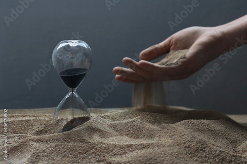 The passage of time is like the life of people. Hand and hourglass. A photo with meaning.