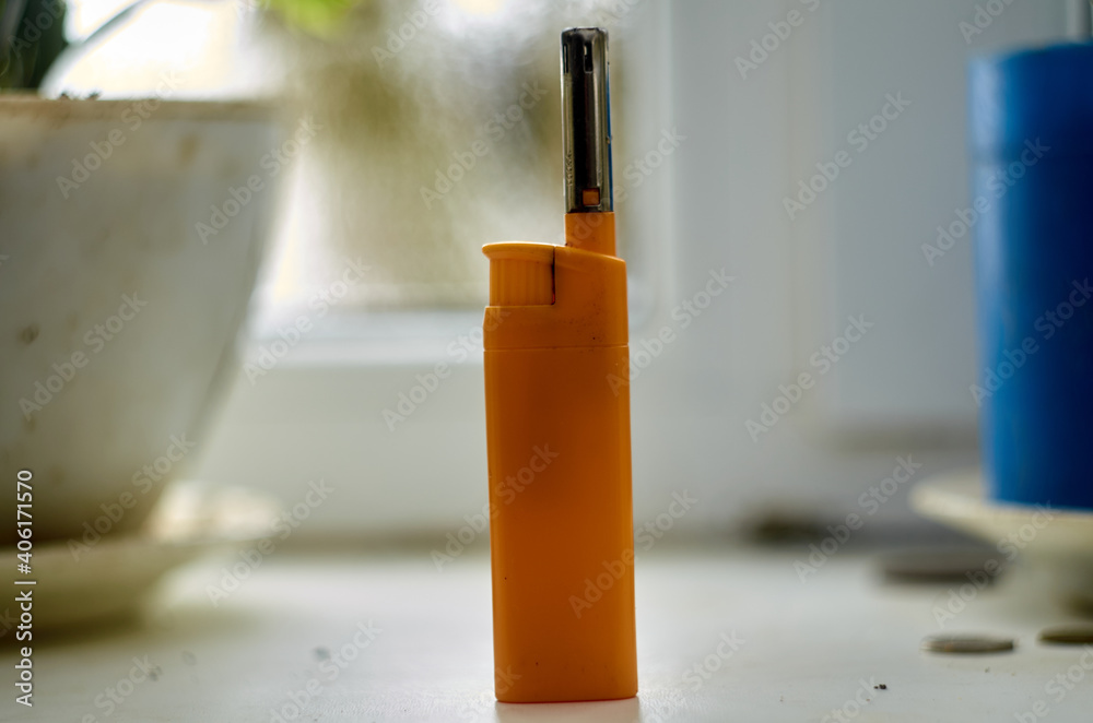 Yellow gas lighter on the windowsill Yellow gas lighter on the windowsill