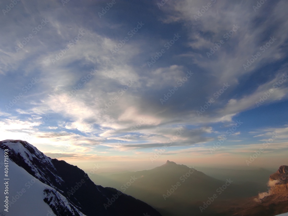 Sunset and clouds behind the snowy mountains of Caucasus shot from the top of mountain 