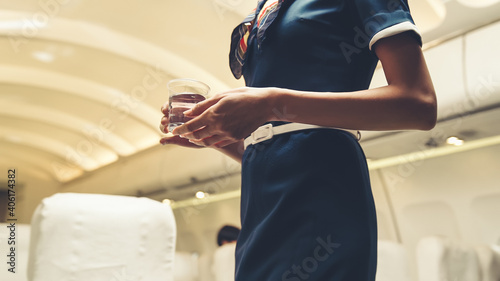 Leinwand Poster Cabin crew serve water to passenger in airplane