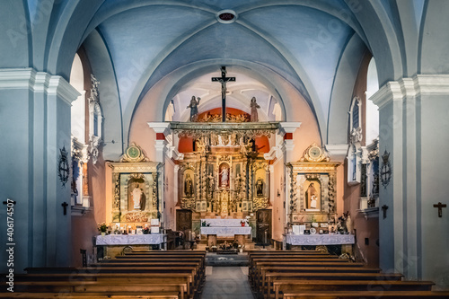 Fotografija Inside a small christian church with wooden cross, golden altar and statues of s