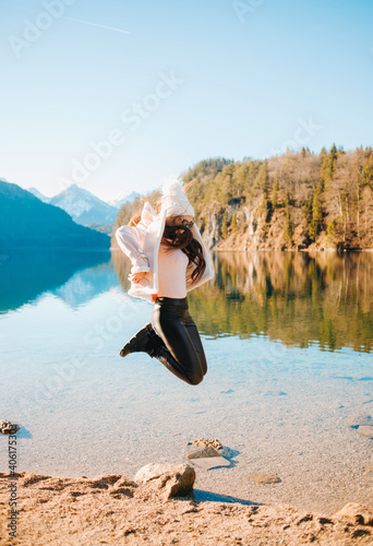 Happy girl jumps on a background of mountains and lake. Winter vacation  Bavaria.