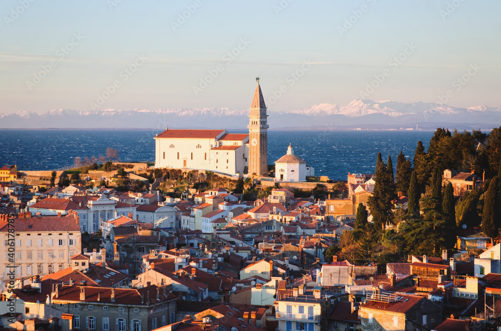 Red roofs of the historical center of old town Piran with main church against the sunset sky and Adriatic sea. Aerial view, Slovenia