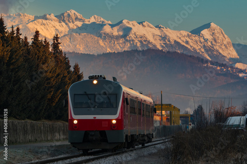 Old diesel train or multiple unit driving towards the city with majestic morning mountains in the background.