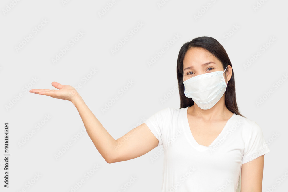 Young woman wearing medical mask standing over isolated white background smiling cheerful presenting with palm of hand looking at the camera Young woman wearing medical mask standing over isolated white background smiling cheerful presenting with palm of hand looking at the camera
