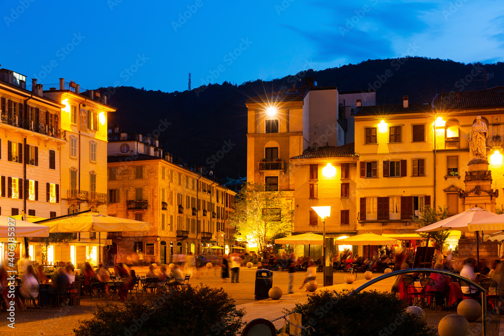 The streets and buildings of Como city in evening near mountains in Italy
