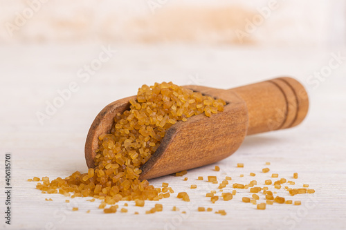 Brown cane sugar sand in a wooden spoon