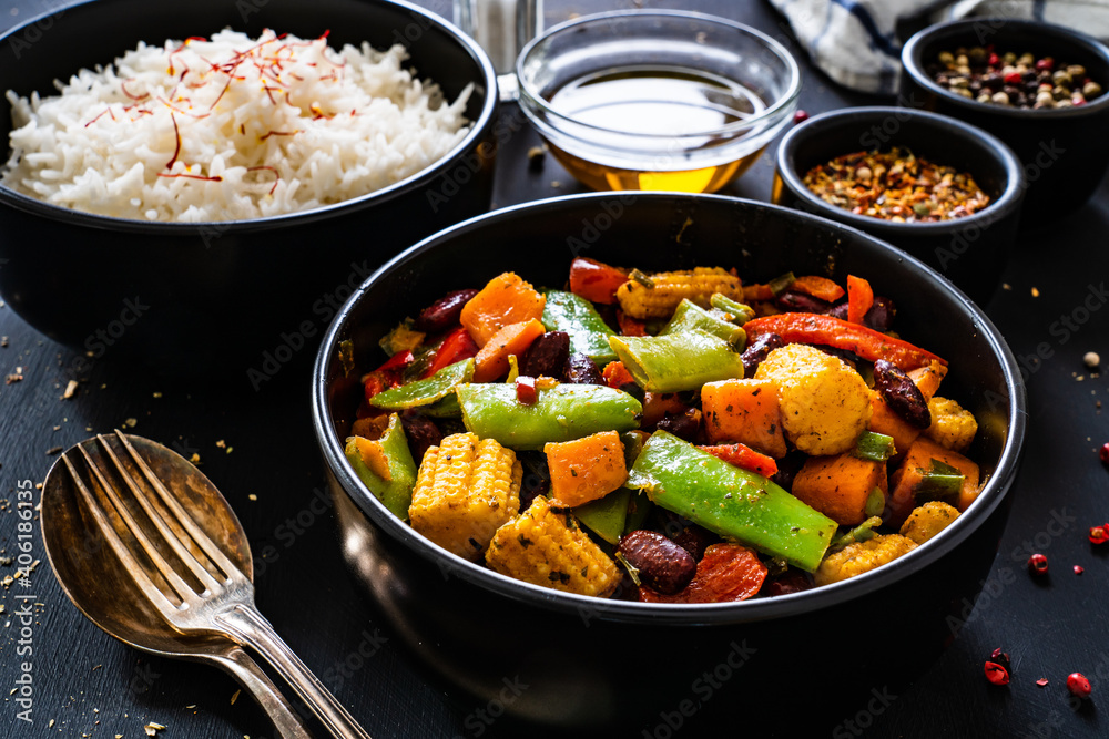 White rice with mix of vegetables on black wooden table
White rice with mix of vegetables on black wooden table