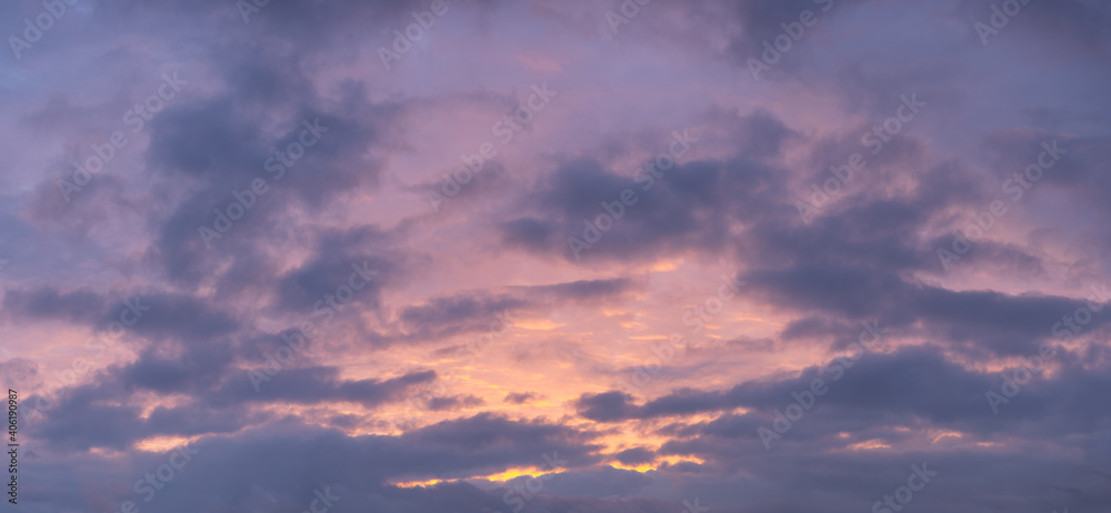 Colorful sunset panorama after a thunder storm. Beautiful sky with clouds in orange and purple. Scenic cloudscape during unstable weather.
