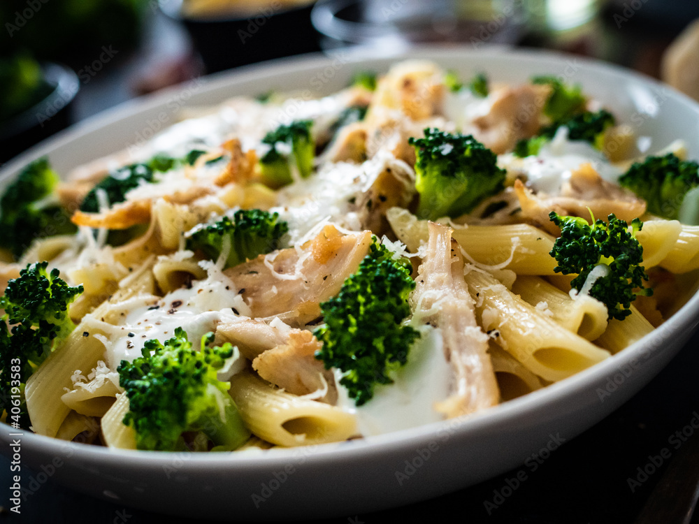 Penne with roast chicken meat, broccoli, parmesan and cream sauce  on black wooden table