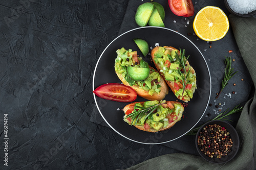 Three toasts with guacamole and rosemary on a black background. Top view, with space to copy. The concept of healthy food.