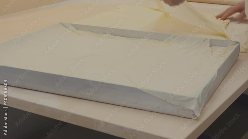 the baker places ultra-thin layers of dough on a baking sheet to prepare a baklava. the baker places ultra-thin layers of dough on a baking sheet to prepare a baklava.