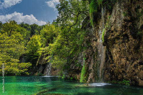 Waterfalls coming down from tall cliffs or rocks to turquoise coloured lake in Plitvice Lakes National Park UNESCO World Heritage, Croatia