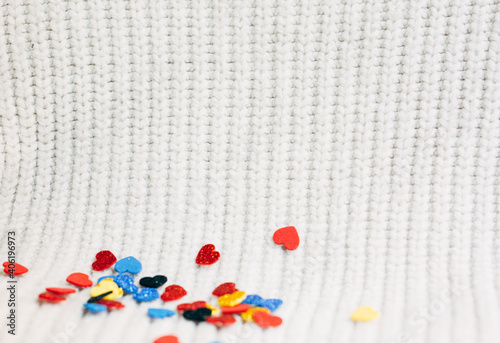 soft focus. Valentine day. multicolored decorative shiny hearts out of focus on white knitted background