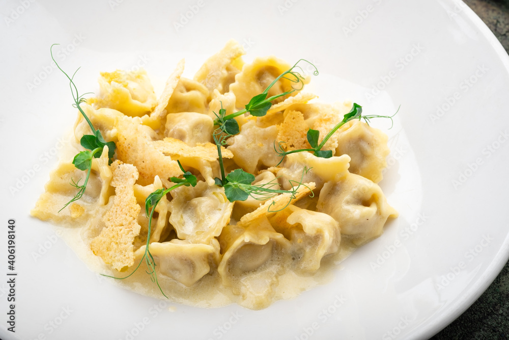 Tortellini with duck, croutons and cheese sauce on a white plate, macro