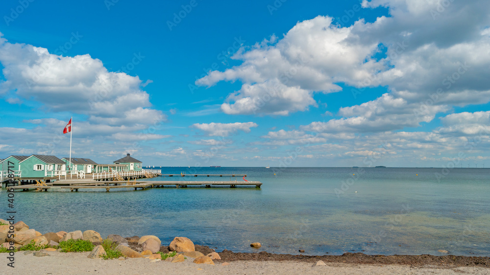 Panoramic view over Baltic seaside beach and Danish National flag near Copenhagen, Denmark, with blue sky and sunny day.
