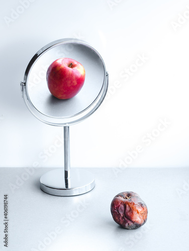 Rotten apple reflection in mirror, depression and narcissism concept, young vs old