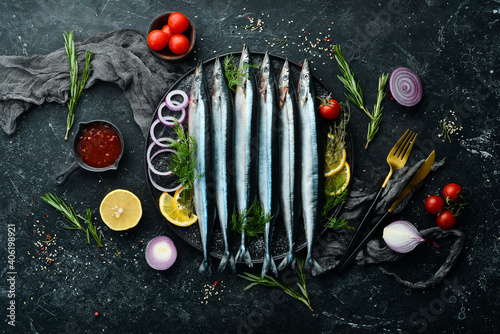 Raw fresh fish Saira with spices on a black stone plate. Seafood. On a dark background. photo