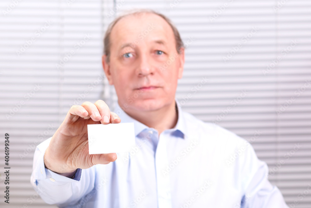 A man in the office at the computer holds a business card in his hands. A man in the office at the computer holds a business card in his hands.
