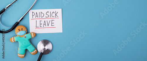 a gingerbread man in a mask and a medical phonendoscope with the inscription paid sick leave on a blue background