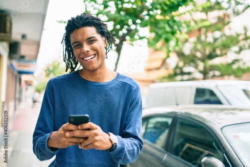 Young african american man smiling happy using smartphone at street of city.