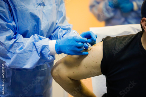 Details with a man getting an intramuscular injection with the Sars-Cov-2 vaccine in a hospital from a medical worker.