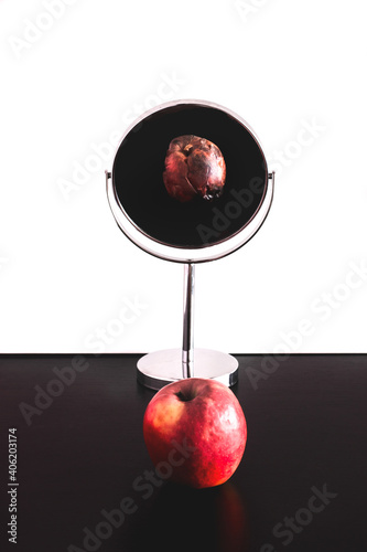 Rotten apple reflection in mirror, depression and narcissism, or young and old concept