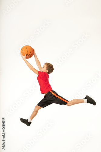Adorable sporty boy holding basketball ball and jumping © Friends Stock