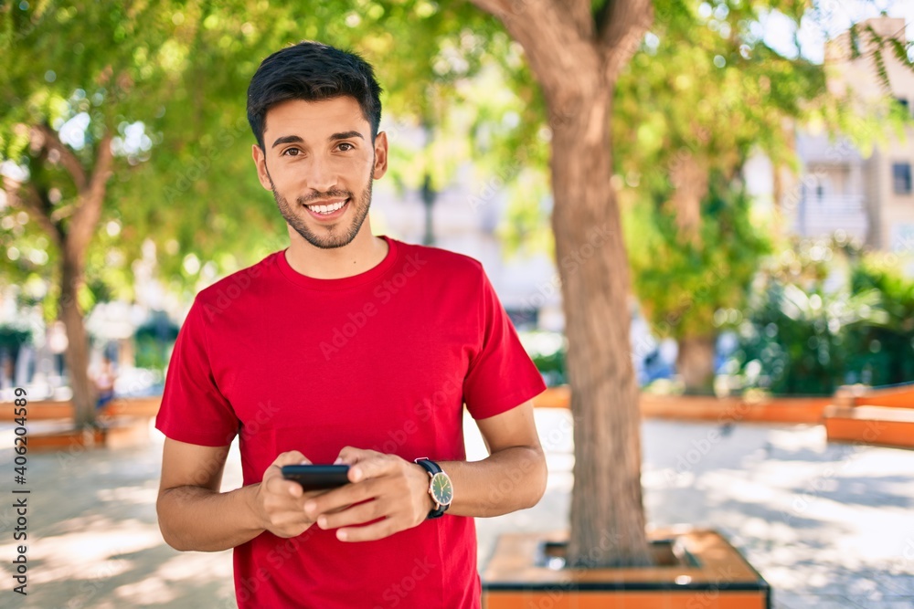Young latin man smiling happy using smartphone walking at the city. Young latin man smiling happy using smartphone walking at the city.