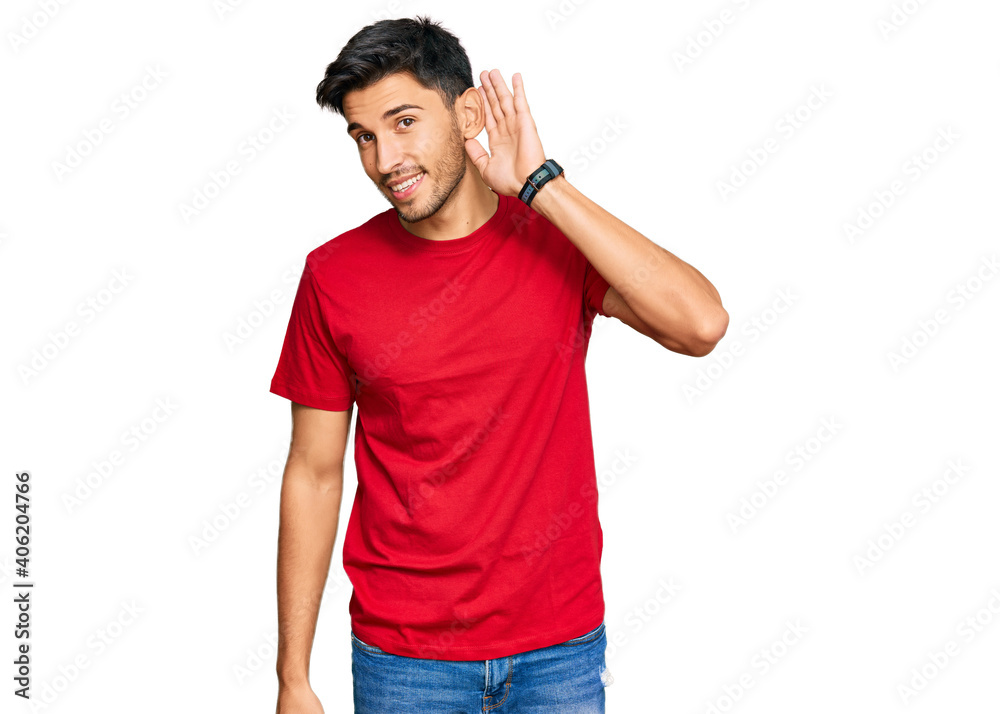 Young handsome man wearing casual red tshirt smiling with hand over ear listening an hearing to rumor or gossip. deafness concept. Young handsome man wearing casual red tshirt smiling with hand over ear listening an hearing to rumor or gossip. deafness concept.