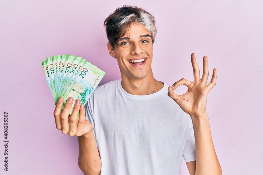 Young hispanic man holding russian 200 ruble banknotes doing ok sign with fingers, smiling friendly gesturing excellent symbol Young hispanic man holding russian 200 ruble banknotes doing ok sign with fingers, smiling friendly gesturing excellent symbol