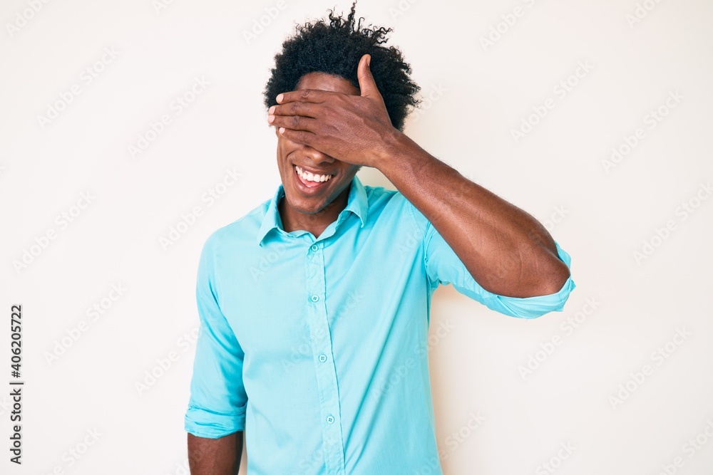 Handsome african american man with afro hair wearing casual clothes smiling and laughing with hand on face covering eyes for surprise. blind concept. Handsome african american man with afro hair wearing casual clothes smiling and laughing with hand on face covering eyes for surprise. blind concept.
