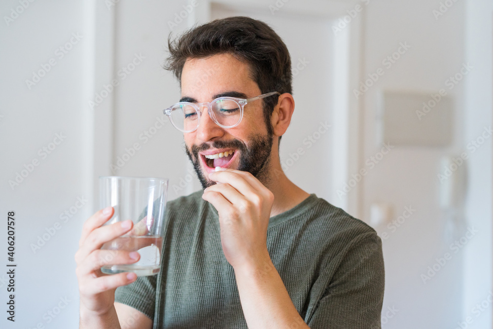 Young man drinking medicine at home Young man drinking medicine at home