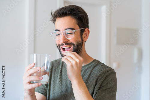 Young man drinking medicine at home