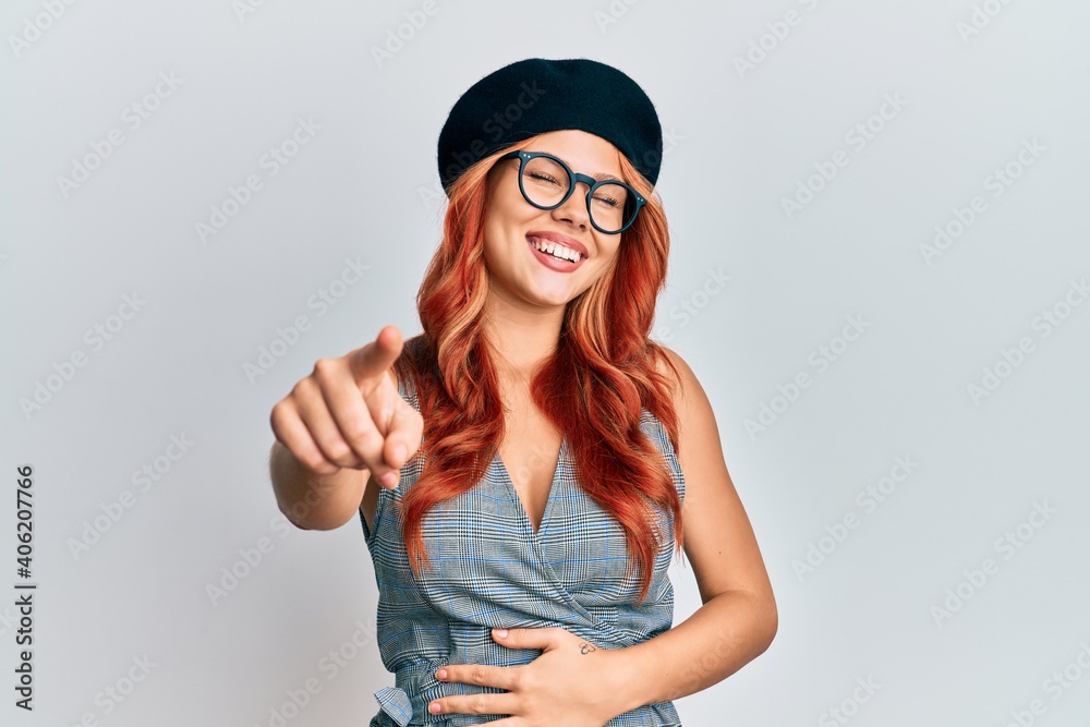 Young redhead woman wearing fashion french look with beret laughing at you, pointing finger to the camera with hand over body, shame expression Young redhead woman wearing fashion french look with beret laughing at you, pointing finger to the camera with hand over body, shame expression