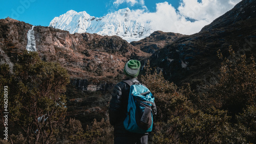 Hiker looks at waterfall and Chakrarahu peak on trail to Lagoon 69 in Cordillera Blanca, Peru. 