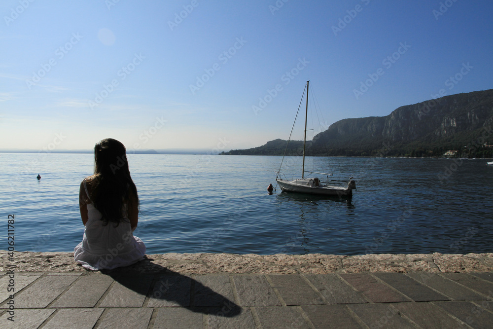 Girl sitting and thinking on the esplanade at lake garda Girl sitting and thinking on the esplanade at lake garda
