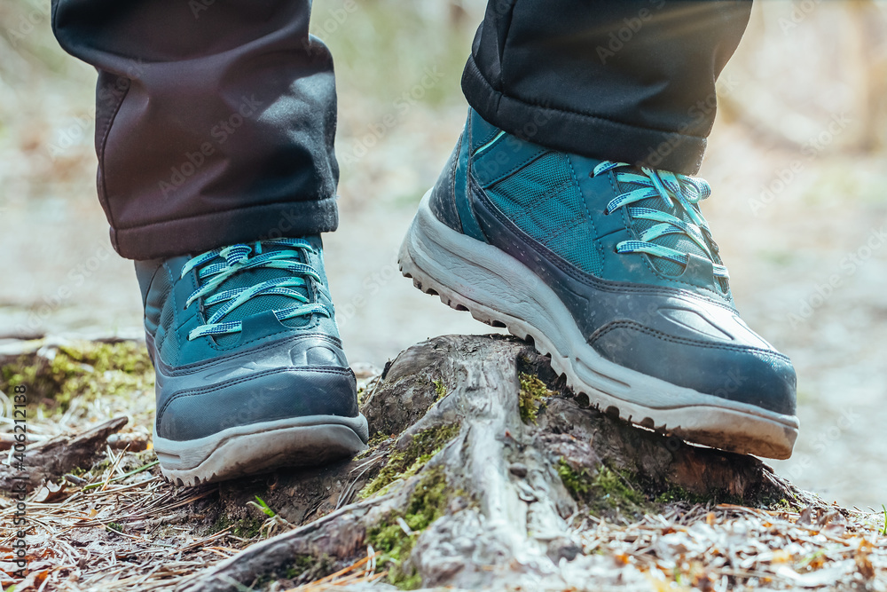 Female hiker on a hiking trail in forest, view from the ground of legs and boots walking