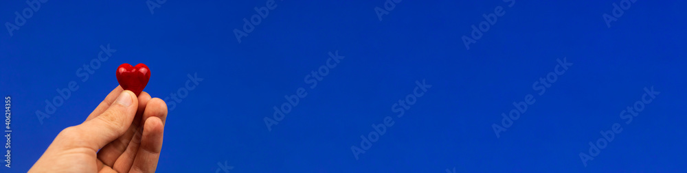 Man hold red heart, giving a love concept, Valentine's Day banner on a blue background, copy space Man hold red heart, giving a love concept, Valentine's Day banner on a blue background, copy space